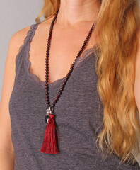 Rosary mala 108 beads from natural stones Garnet are worn on a girl in a grey shirt. Author's jewelry from natural stones, Buddhism, matra, prayer, rosary from stones for prayer and beauty