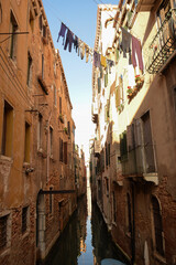 Fototapeta na wymiar A canal in Venice, Italy, between old buildings with the washed clothes of residents hanging between them