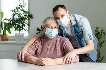 family, generation and people concept - happy smiling senior mother with adult son hugging at home