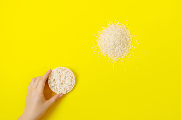 Fototapeta na wymiar Rice cake in woman arm on a yellow background, rice grains in the left coner.