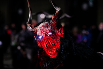Krampus night parade, People in scary fur costumes and masks with hornes walk on the street,...