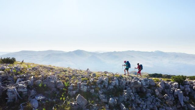 4K dynamic aerial drone footage of a backpackers couple with backpacks and trekking poles hiking by the Dinaric Alps mountain Range. Sinjal or Dinara (1831 m) mountain - the highest point of Croatia.