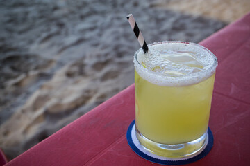 Mezcal Margarita made with fresh lime juice served in a glass with a paper straw on the beach of Lo De Marcos, Nayarit, Mexico.
