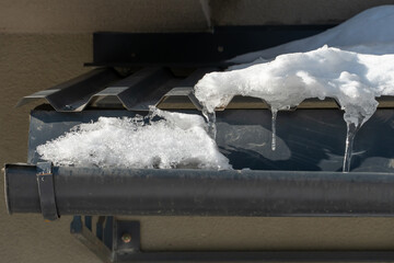 The houses are covered with snow and covered with ice after the snowfall. Falling icicles are...