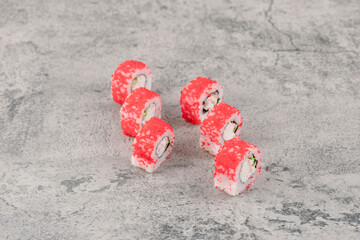 Delicious sushi rolls decorated with red caviar on marble table