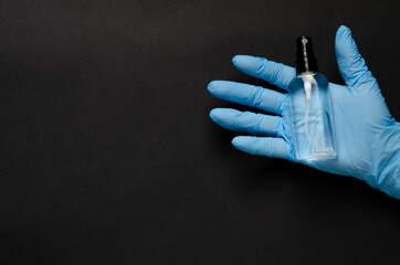 Hand sanitizer bottle in gloved hand closeup.Antibacterial liquid against 19-ncov.Black background. Call for hand disinfection. Stop coronavirus concept. 