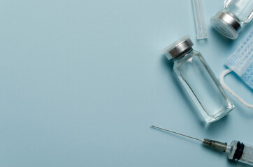 Medical concept, jars with covid vaccine, syringe, on a blue background. Place for text.Immunization and treatment of coronavirus infection.