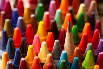Color crayons in a tight group, shot from above with a pencil among them, showing individual standout - obrazy, fototapety, plakaty