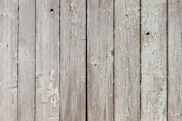 Part of an old fence of painted wooden boards on the street. Old wooden fence made of flat boards. Faded texture with peeling paint. Copy space