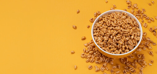 Puffed wheat cereal isolated on yellow background, top view
