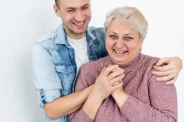 family, generation and people concept - happy smiling senior mother with adult son hugging at home