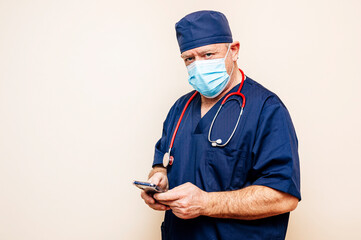 Veteran doctor using smart phone with beige background