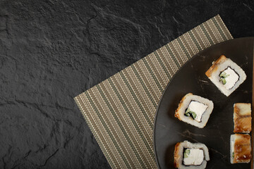 Tasty dragon sushi rolls with eel on black plate