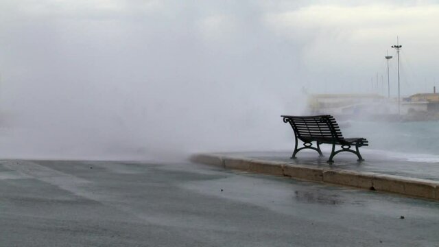 a bench by the sea at the mercy of the storm and rough seas covered by a big wave
