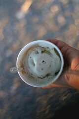 Hand holding a cup of ice cream at sunset. Selective focus.