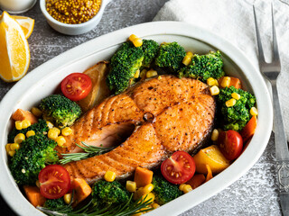 roast, fried, baked fish steak salmon, trout with broccoli and carrots, in ceramic baking dish, top view 