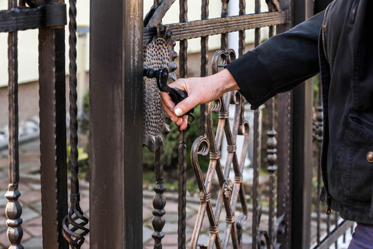 Wrought Fence. Woman Hand opening metal fence gate
