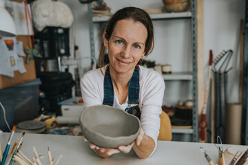 young artisan woman working with her hand a piece of ceramic