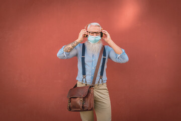 an older an older man in hipster clothes and glasses and long white beard listens to music focus on head