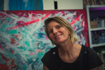 Young woman paints an abstract picture with her hands in her interior studio