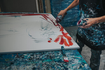 Young woman paints an abstract picture with her hands in her interior studio