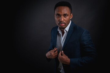 Portrait of attractive, handsome, cute, serious and stylish professional african american businessman executive with stylish suit and white shirt isolated on dark background. Low key. Selective focus