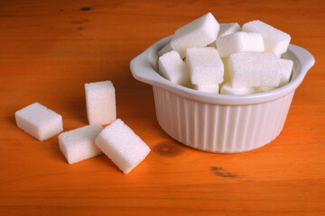 Bowl full of sugar cubes on wooden table.