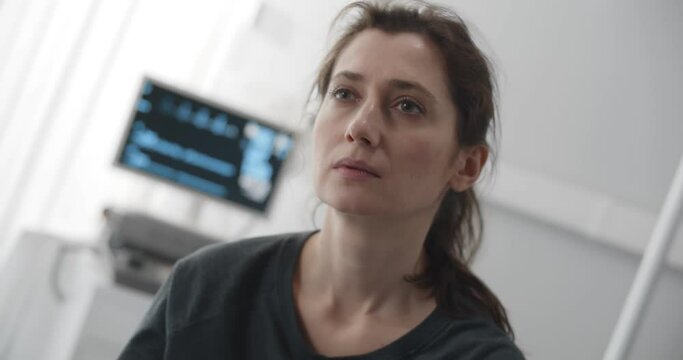 Sick woman feeling dizzy sitting on bed in hospital ward