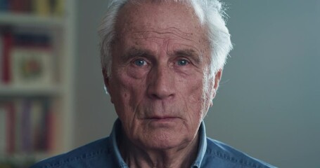 Cinematic shot of happy senior pensioner man is smiling in camera in living room at home. Concept of life, family, achievement, father, husband, grandfather, elderly, retirement, boarding house. - Powered by Adobe