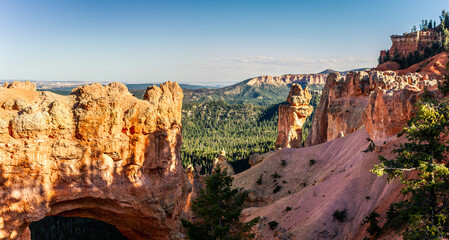 Fototapeta premium Sandstone arch with small conifers in Bryce canyon national park in Utah before sunset, america