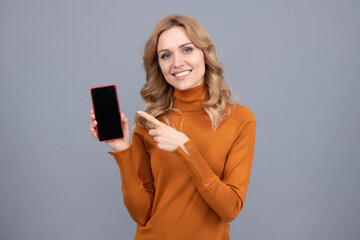 Naklejka premium Happy girl pointing finger at mobile phone. Pointing index finger for advertising