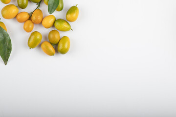 Fresh ripe kumquats with leaves on white background