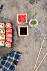 Fototapeta na wymiar Plate of various delicious sushi rolls with soy and wasabi on marble table