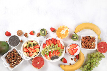 Healthy breakfast with ingredients, fruit salad with strawberries, muesli, grapes, banana and chia seeds for weight loss. The concept of natural nutrition and detox diet, lifestyle, selective focus,