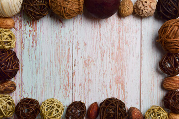 Different types, colors and composition of wicker decorative balls lie around the perimeter on a wooden background