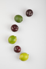 Fresh limes and cherry plums isolated on white background