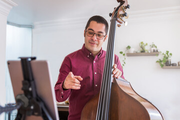 Young man teaching live music with his tablet. He teaches how to play the double bass