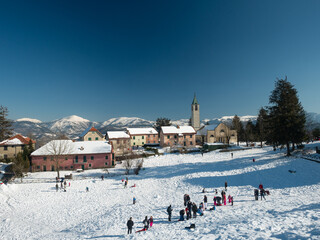 people play in the snow in a small mountain village