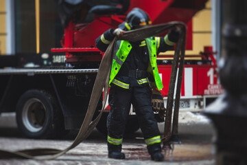 Group of fire men in uniform during fire fighting operation in the city streets, firefighters with...