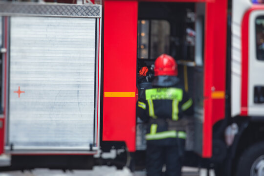 Group of fire men in uniform during fire fighting operation in the city streets, firefighters with the fire engine truck fighting vehicle in the background, emergency and rescue