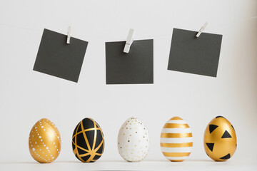 Easter golden decorated eggs stand in a row with black text stickers above them on white background. Minimal easter concept. Happy Easter card with copy space for text. Top view, flatlay.