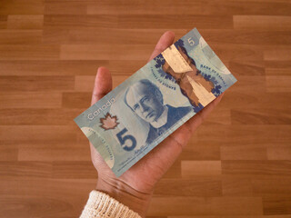 Woman holding 5 Canadian dollars. Money