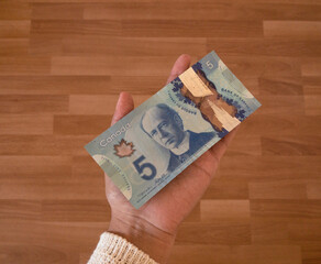 Woman holding 5 Canadian dollars. Money