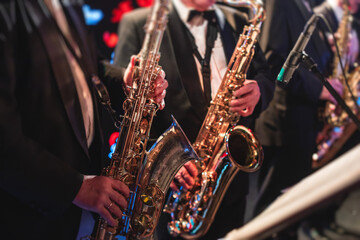 Obraz premium Concert view of a saxophonist, saxophone sax player with vocalist and musical during jazz orchestra performing music on stage