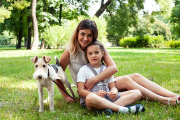 Obraz premium young pretty caucasian mother walking with little cute daughter and dog fox terrier, lifestyle people concept