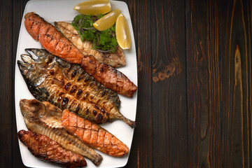 Grilled fish on a white plate with herbs and lemon, dorado, mackerel, salmon steak, salmon fillet,...