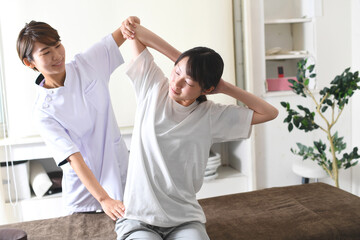 Obraz premium 整体（カイロプラクティック）を受けるストレッチ中の若い女性