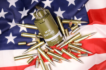 M18 smoke grenade and many yellow bullets and cartridges on United States flag. Concept of gun...