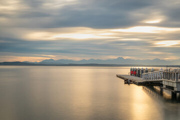 Fototapeta na wymiar Long exposure photography of the bay in Seattle with a pier during sunset, calm water, golden hour.