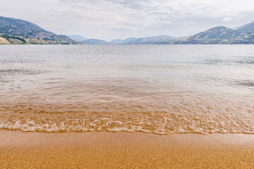 beautiful quiet morning on the lake beach with yellow sand.